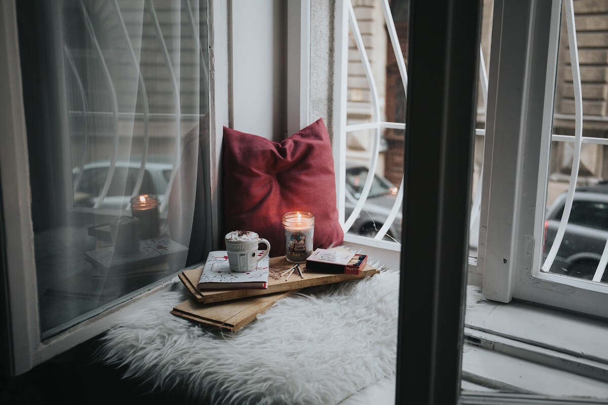 comfortable place to sit by window, red cushion, candle